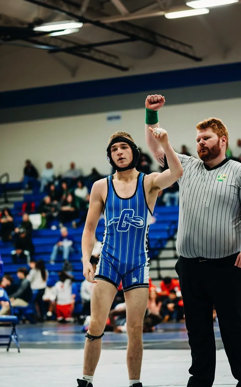 High-school Nathan Johnson with his hand raised by the referee after a wrestling win